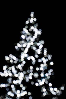 Güzel bulanık ışıklar siyah bir arka planda Noel ağacını aydınlatıyor.