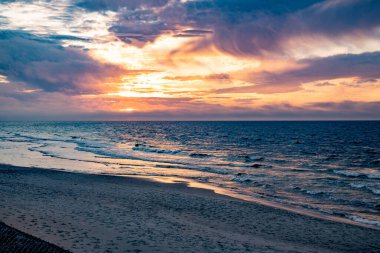 Polonya 'da Baltık Denizi' nin kıyılarında renkli bulutlarla sakin bir gün batımı.