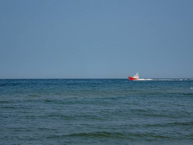 Küçük beyaz ve kızıl bir kurtarma gemisi sıcak bir yaz gününde Polonya Baltık Denizi 'nde mavi gökyüzüne doğru yol alıyor.