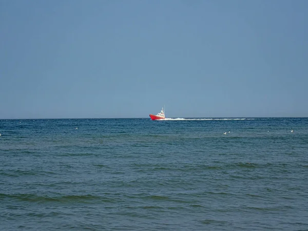 small white and red sea rescue vessel sailing on the Polish Baltic Sea against the blue sky on a warm summer day