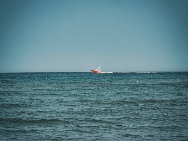 small white and red sea rescue vessel sailing on the Polish Baltic Sea against the blue sky on a warm summer day