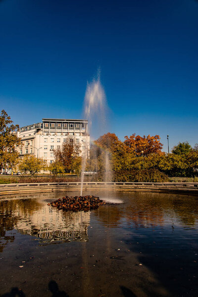 beautiful autumn urban landscape in Warsaw Poland with a fountain and trees