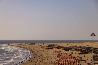 İspanyol Kanarya Adası Gran Kanaryası 'nda kumsalı olan güneşli bir manzara.