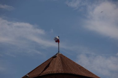 Yazın kiremitli binanın çatısında kırmızı ve beyaz bayrak sıcak güneşli bir günde mavi gökyüzü arka planında