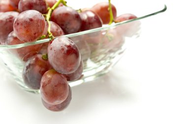 Beyaz arka plan üzerinde izole cam kase içinde pembe üzüm demet