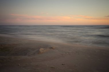 uzun pozlama ile kumlu deniz sahilde günbatımı