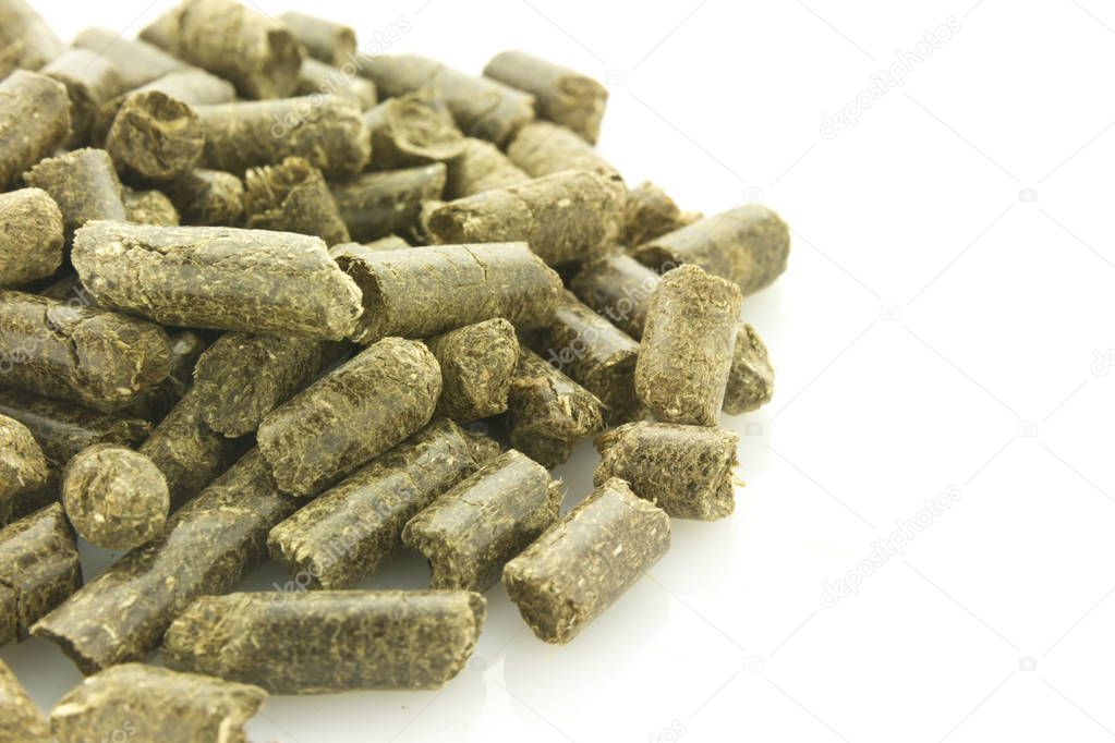 heap of grass pellets, symbol of renewable energy, isolated on white reflective background