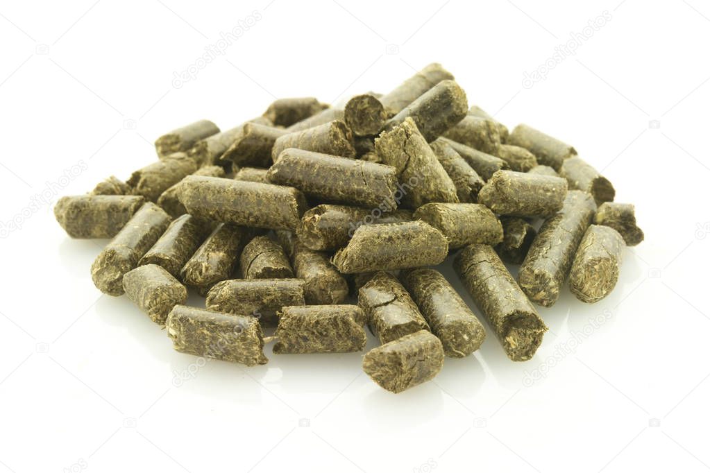 heap of grass pellets, symbol of renewable energy, isolated on white reflective background