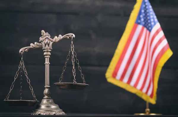 Law and Justice, Legality concept, Scales of Justice in front of the American flag in the background.