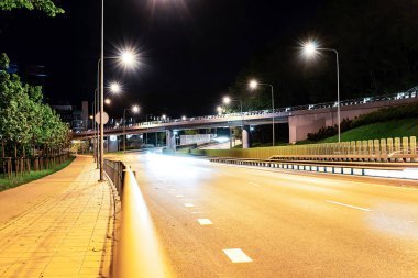 Asfalt yol ve yükseltilmiş köprü aydınlatan lambalar ile gece