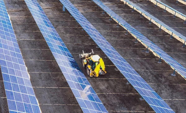 Tractor amarillo entre filas de paneles solares - una vista superior —  Fotos de Stock