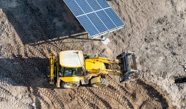 Tractor amarillo entre filas de paneles solares - una vista superior —  Fotos de Stock