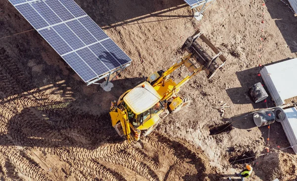 成排太阳能电池板之间的黄色拖拉机-顶视图 — 图库照片