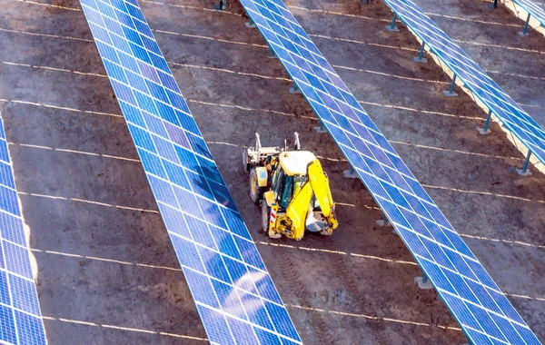 Gelber Traktor zwischen Solarpaneelen - eine Ansicht von oben — Stockfoto