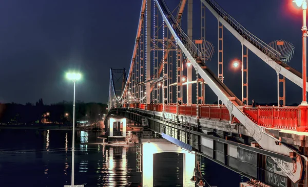 Pedestrian metal bridge with colored lights across the river Royalty Free Stock Images