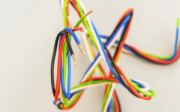 Fils électriques de différentes couleurs sous forme courbée sur un dos gris — Photo