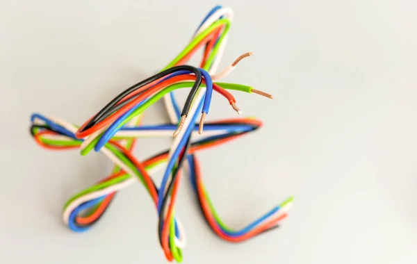 Ηλεκτρικά σύρματα διαφορετικών χρωμάτων σε καμπυλωτή μορφή σε γκρι πλάτη — Φωτογραφία Αρχείου