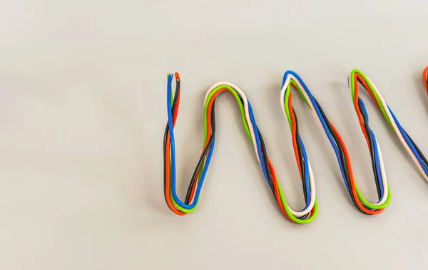 Elektriska ledningar av olika färger i böjd form på en grå bak — Stockfoto