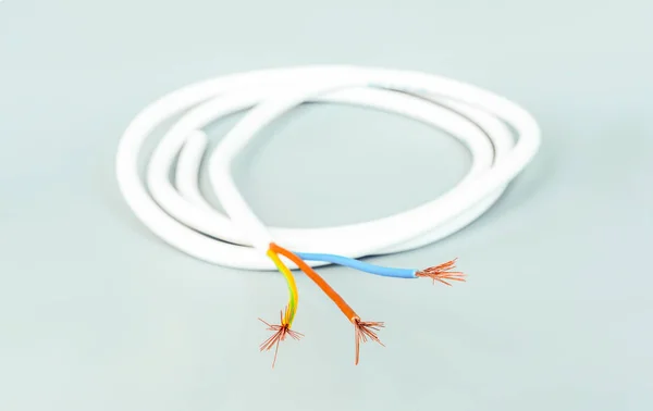 Gri arka plan üzerinde beyaz izolasyonlu üç çekirdekli kablo — Stok fotoğraf