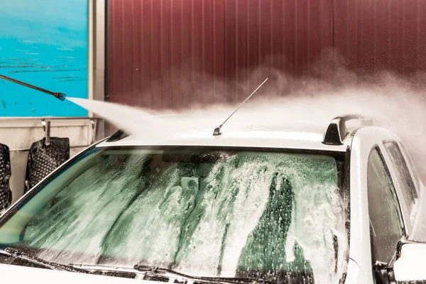 Das Waschen eines weißen Autos mit einem Hochdruckreiniger — Stockfoto