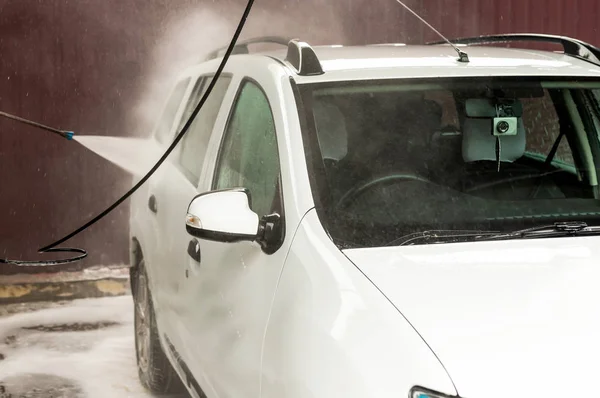 O processo de lavagem de um carro branco usando uma arruela de pressão — Fotografia de Stock