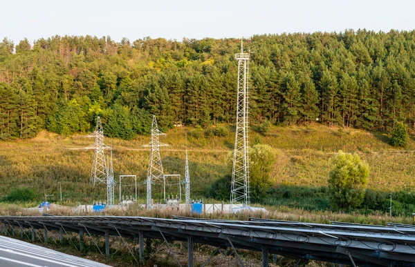 Solpaneler på en bakgrund av kraftledningar bland skogen — Stockfoto