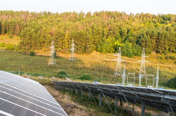 Panele słoneczne na tle linii energetycznych w lesie — Zdjęcie stockowe