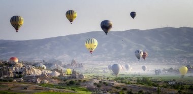 Kapadokya Türkiye 'de kayaların üzerinde uçan sıcak hava balonu