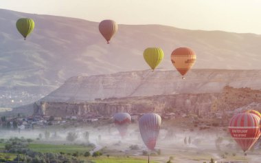 Kapadokya Türkiye 'de kayaların üzerinde uçan sıcak hava balonu