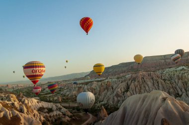 Kapadokya Türkiye 'de kayaların üzerinde uçan sıcak hava balonu 