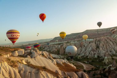 Kapadokya Türkiye 'de kayaların üzerinde uçan sıcak hava balonu 
