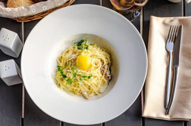 Makarna Carbonara parmesan ve beyaz arka plan üzerinde sarısı ile beyaz plaka üzerinde