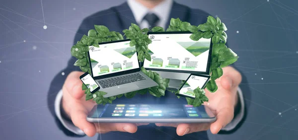 View of a Businessman holding connected devices surrounding by leaves 3d rendering