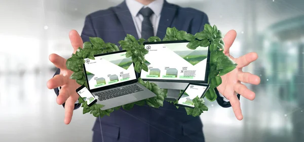 View of a Businessman holding connected devices surrounding by leaves 3d rendering
