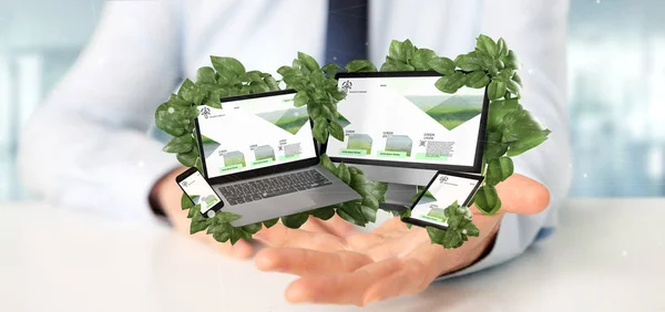 View of a Businessman holding connected devices surrounding by leaves 3d rendering