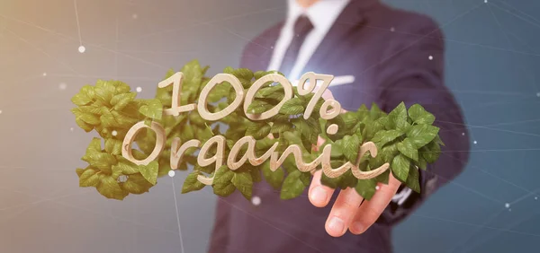 Businessman holding a Wooden logo 100 % organic with leaves arou — Stock Photo, Image