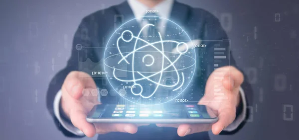 Businessman holding an atom icon surrounded by data — Stock Photo, Image