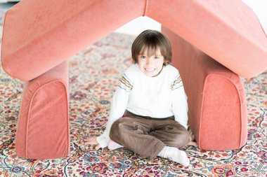 Ev yapımı ev çatı ile oynayan uzun saçlı küçük çocuk