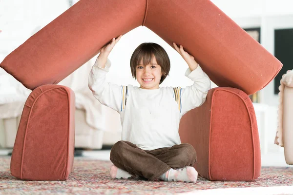 Liten pojke med långt hår spelar på hem gör hus med tak — Stockfoto