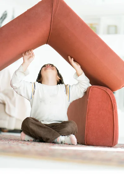 Niño con el pelo largo jugando en casa haciendo casa con techo — Foto de Stock