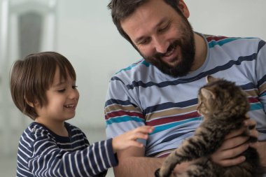 Yetişkin adam ve küçük oğluyla evde kedisi