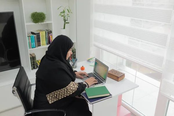 在办公室使用笔记本电脑工作的年轻穆斯林妇女 — 图库照片
