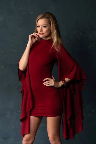 Tall slender blonde in a short red dress with voluminous sleeves