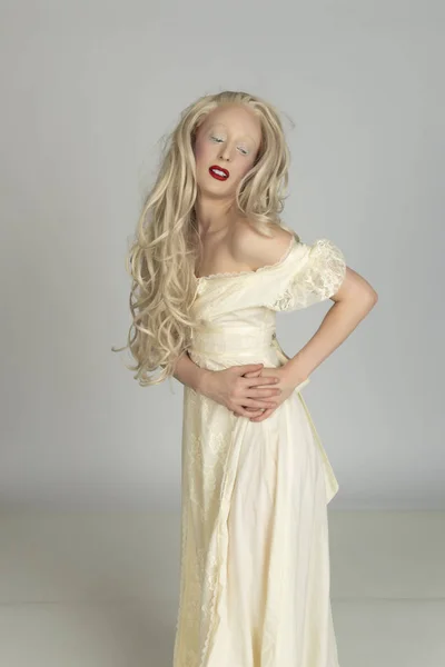 Pale young blonde woman in a yellow dress