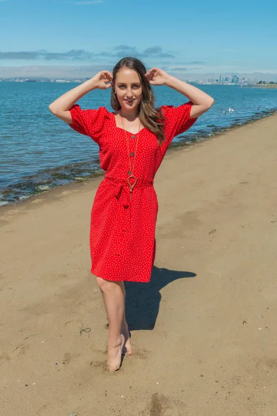 Brunette in red on a beach — Stock Photo, Image