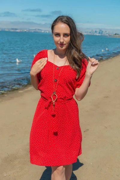 Brunette i rødt på en strand – stockfoto