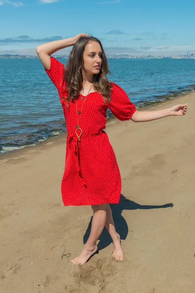 Brunette in red on a beach — Stock Photo, Image