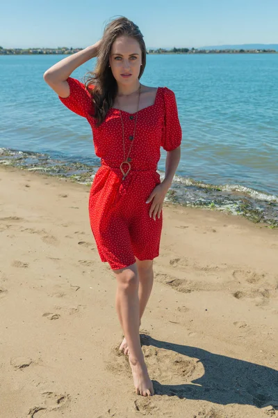 Brunette in red on a beach — Stock Photo, Image