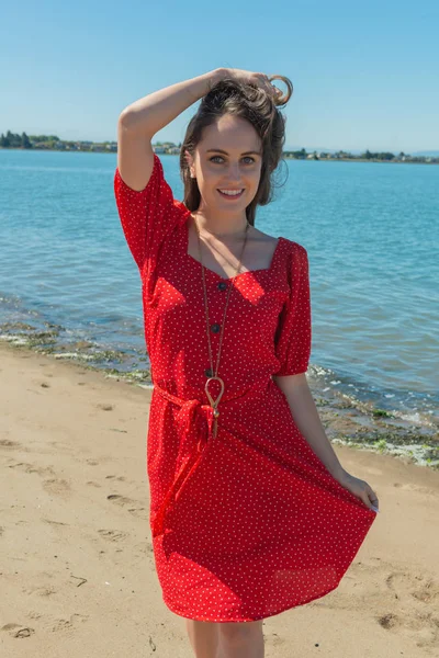 Brunette in red on a beach — Stock Photo, Image