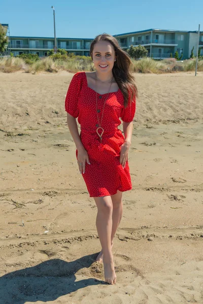 Brunette in red on a beach — Stock Photo, Image